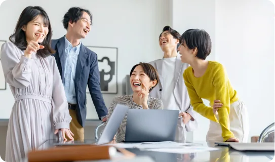 社員がノートパソコンを囲んで笑顔で話している様子